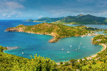 A panoramic view of English Harbour in Antigua, featuring a bay with sailboats surrounded by lush green hills.