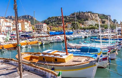 Boats in harbour of cassis on a sunny day cliffs in the background.