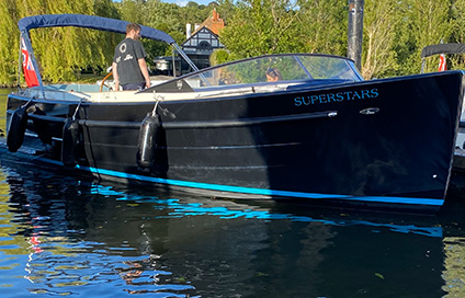 Superstars private boat on the water during the Henley Royal Regatta with people on board.