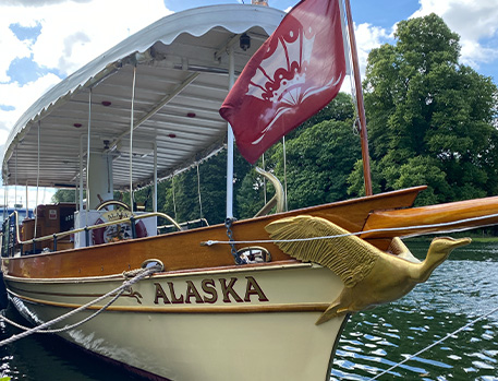 Thames River boat on water with red flag waving and bird ornament.