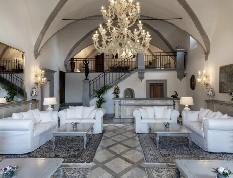 Grand lobby at Monastero di Cortona Hotel, Tuscany, featuring elegant chandeliers, classic furnishings, and vaulted ceilings in a luxurious, historic setting.