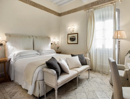 Elegant luxury bedroom suite at Monastero di Cortona Hotel, Tuscany, featuring classic decor, king-size bed, and soft natural light for a serene atmosphere.