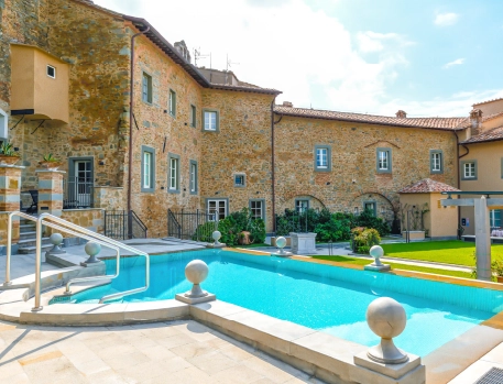 Charming pool area at Monastero di Cortona Hotel, Tuscany, with historic stone walls and modern outdoor amenities.