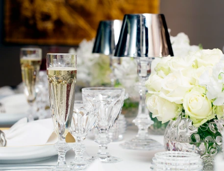 Elegant luxury table setting at The Dorchester's Chef's Table, featuring crystal champagne flutes, white roses, and sophisticated silver lamps for an upscale dining experience.