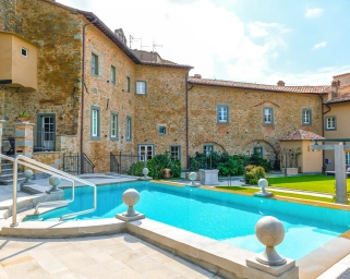 Outdoor pool area at Monastero di Cortona Hotel, Tuscany, showcasing the hotel's historic architecture and modern amenities.