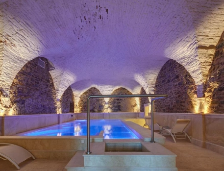 Underground spa pool at Monastero di Cortona Hotel, Tuscany, featuring stone arches and ambient lighting for a luxurious and serene atmosphere.