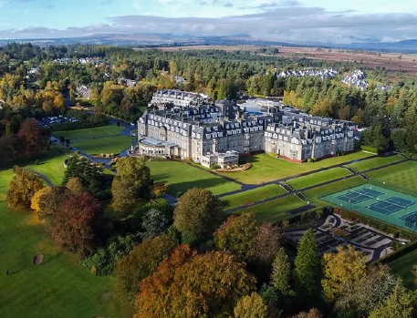 Aerial view of Gleneagles Hotel surrounded by lush greenery and autumn foliage in Scotland.